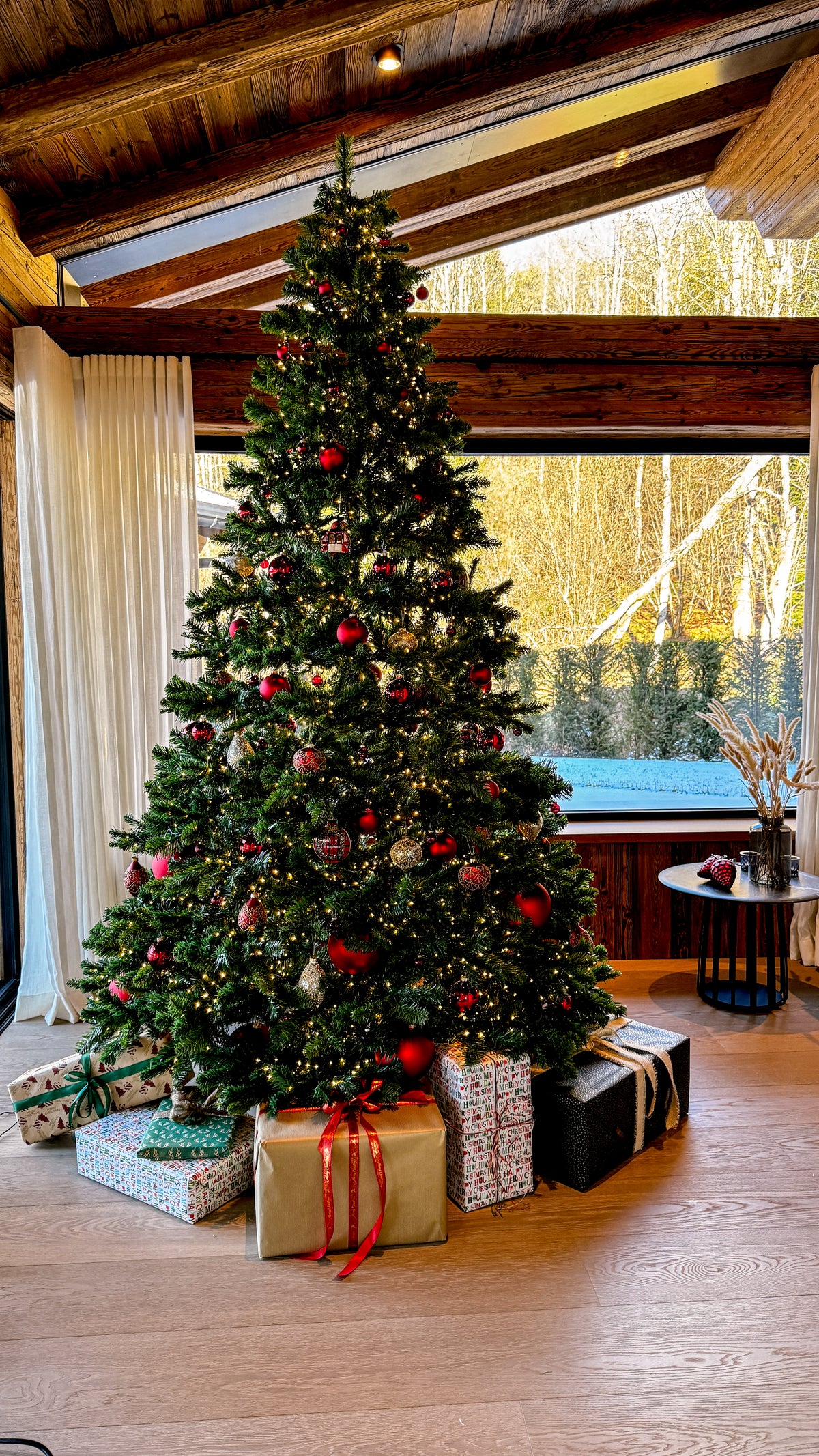 Weihnachtsbaum mit Geschenken in einem Wohnraum mit Holzbalken