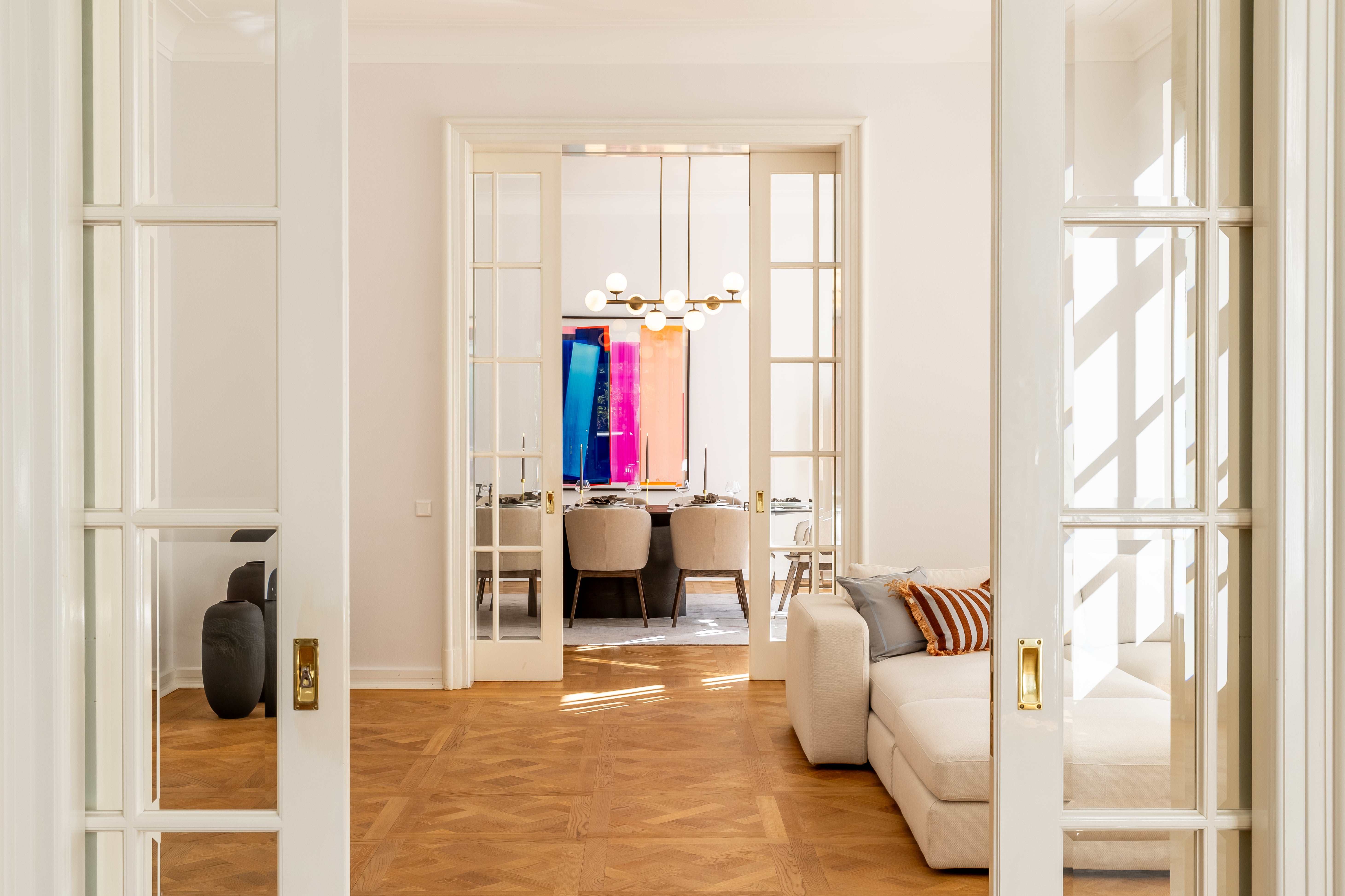 Blick vom Salon in das gedeckte Esszimmer mit Kunstwerk