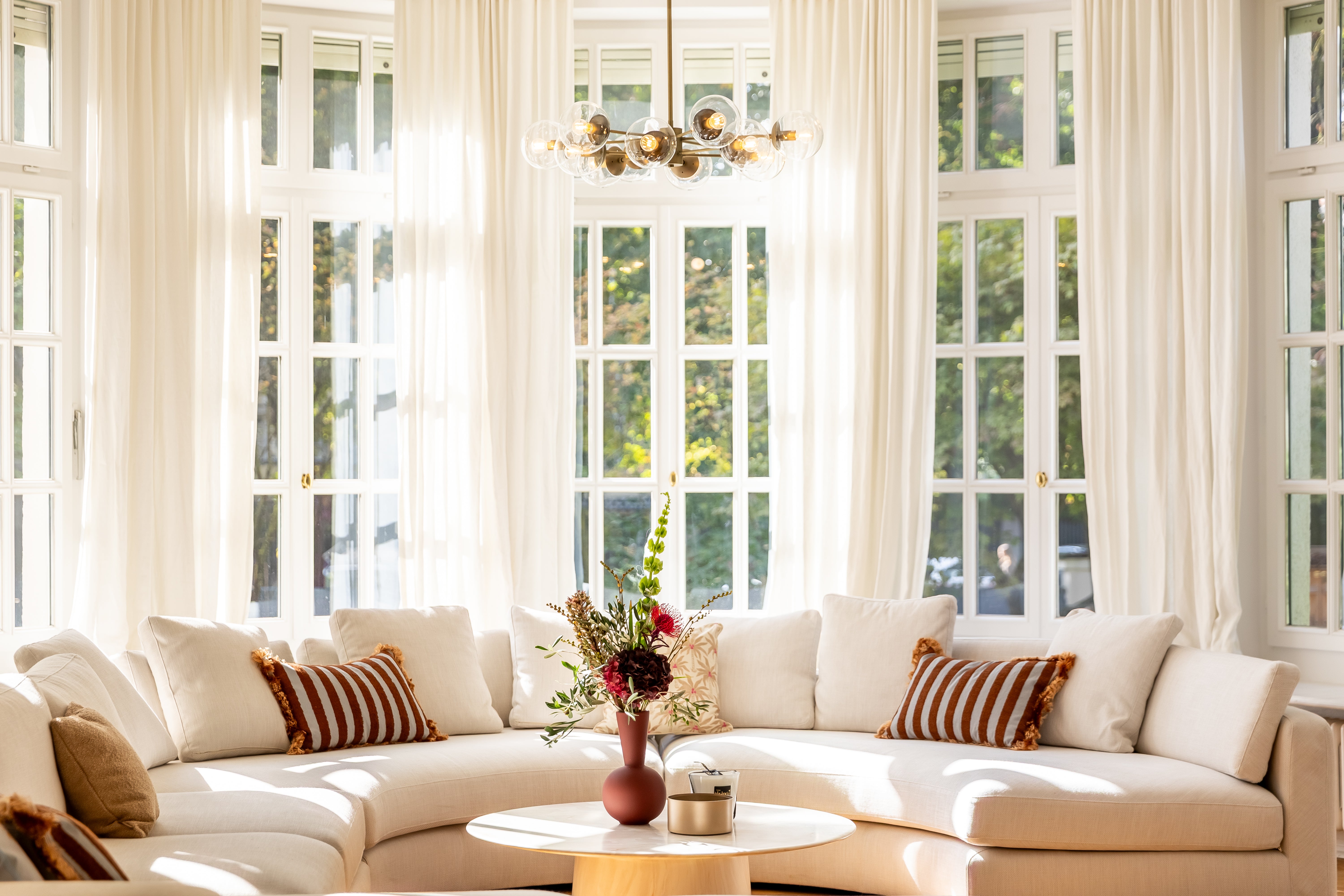 Salon mit rundem Sofa und Blick durch die Flügeltüren ins Esszimmer