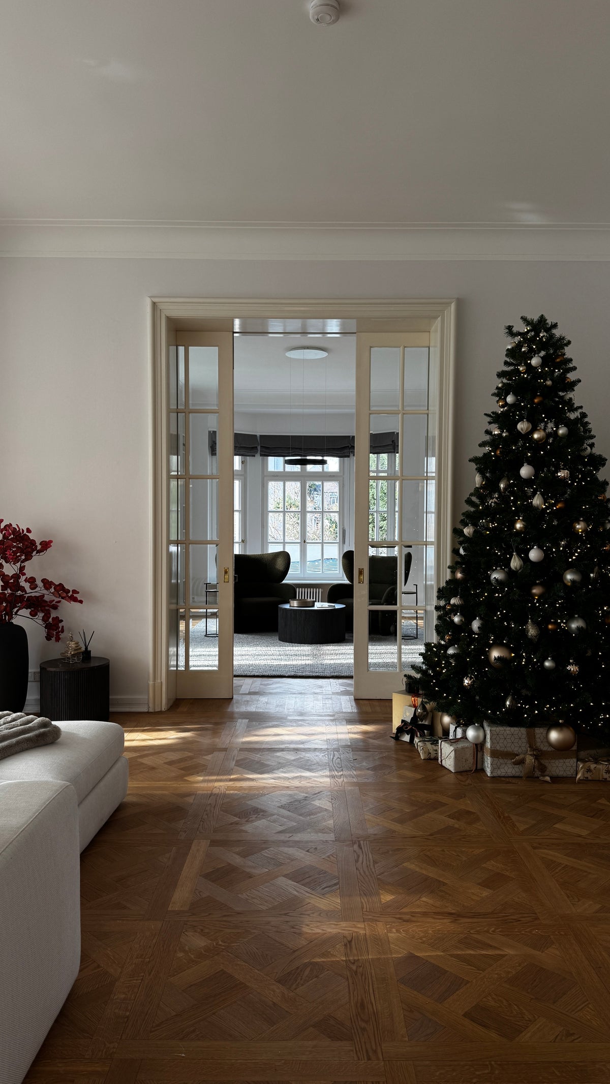 Dunkel geschmückter Weihnachtsbaum in einem hellen Altbau mit Parkett